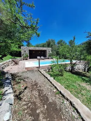 a swimming pool in a yard with a house at Cabañas Posada del Angel in Villa Serranita