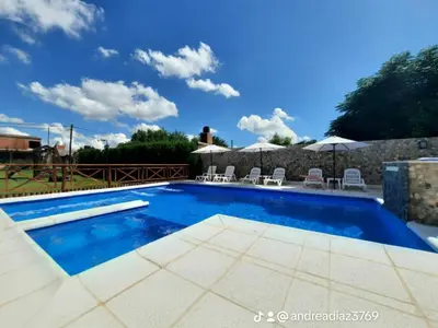 a large swimming pool with chairs and umbrellas at Alojamiento Premium en Las Marias De Cura Brochero in Villa Cura Brochero