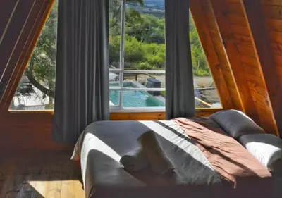 a bedroom with a couch and a large window at Alpinas Iguazu in Bialet Massé