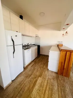 a kitchen with a white refrigerator and a wooden floor at La Serena Villa Rumipal - Cordoba in Villa Rumipal