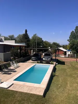 a swimming pool in a yard with two cars parked at La Serena Villa Rumipal - Cordoba in Villa Rumipal