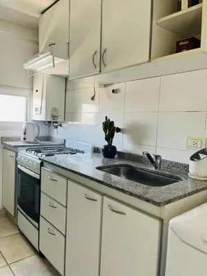 a kitchen with white cabinets and a sink at Depto Ángeles Fragueiro in Cordoba
