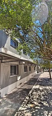 a building with barred windows next to a tree at alojamiento bella vista in Villa Carlos Paz