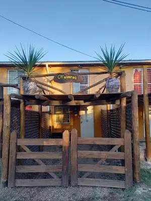 a wooden fence in front of a house with palm trees at Naiarai Cordoba in Santa María