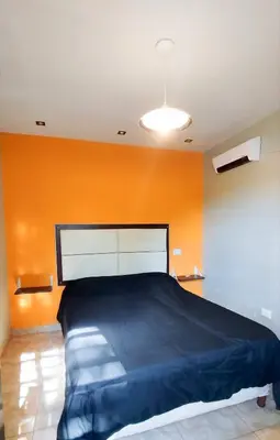 a bedroom with a large bed with an orange wall at Complejo ELMA in San Antonio de Arredondo