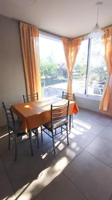 a dining room table with chairs and a large window at Complejo ELMA in San Antonio de Arredondo