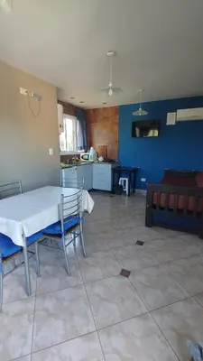 a living room with a table and chairs and a kitchen at Complejo ELMA in San Antonio de Arredondo