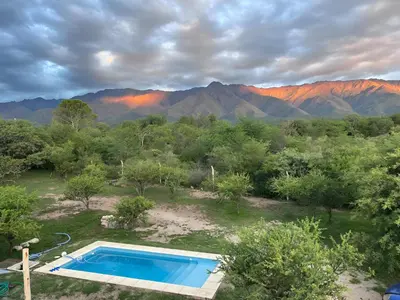 a swimming pool in a field with mountains in the background at Casa con piscina privada y vistas al Cerro Champaquí in San Javier