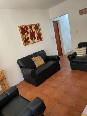 a living room with two black leather couches at Depto Sierra in Santa Rosa de Calamuchita