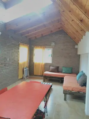 a living room with two beds and a table at Casa Amapola in Embalse