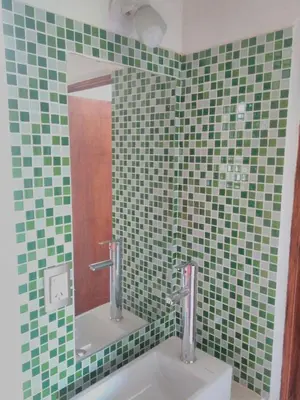 a bathroom with a sink with a mirror and green tiles at Casa Amapola in Embalse
