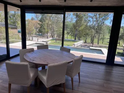 a wooden table and chairs in a room with windows at Casa en Molvento in Villa Los Molinos