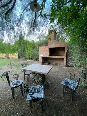 a picnic table with four chairs and a brick oven at Cabañas Enki in La Ramada
