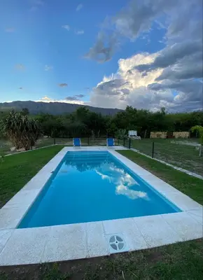 a large blue swimming pool with two chairs in a yard at Cabañas Enki in La Ramada