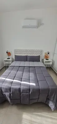 a large bed in a white room with two chairs at Moderno departamento a estrenar in Alta Gracia