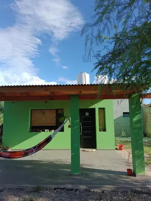 a green house with a hammock in front of it at El buen retiro in Villa de Las Rosas