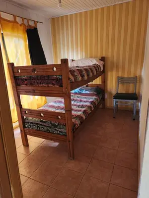 a bedroom with two bunk beds and a chair at Altos de Grecia Cabaña 1 in Villa Carlos Paz