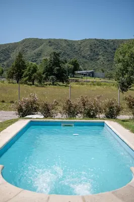 a blue swimming pool with a mountain in the background at Sierras Country Golf in San Antonio de Arredondo