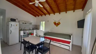 a kitchen and dining room with a table and a bed at Cabaña Trébol en Cabañas Encuentro in Carpintería