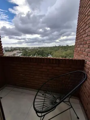 a metal bench sitting on a balcony with a brick wall at Excepcional departamento en Nueva Córdoba in Cordoba