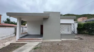 a small white house with a gate in front of it at La casa de Rena in Santa Rosa de Calamuchita