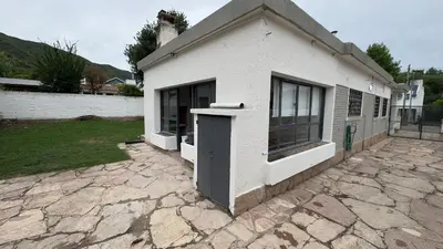 a white building with a door on a stone driveway at La casa de Rena in Santa Rosa de Calamuchita