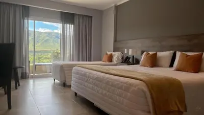 a hotel room with two beds and a large window at Gran Hotel Cosquin in Cosquín