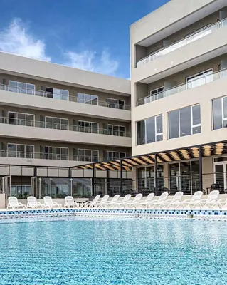 a building with chairs and a swimming pool in front of it at Gran Hotel Cosquin in Cosquín