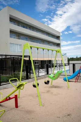 a group of playground equipment in front of a building at Gran Hotel Cosquin in Cosquín