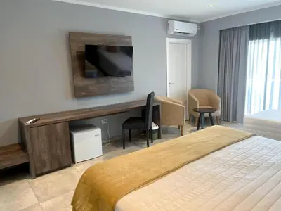 a hotel room with a bed and a desk with a television at Gran Hotel Cosquin in Cosquín