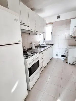 a white kitchen with a stove and a refrigerator at Dpto ob trejo - pileta asador quincho vista a las sierras in Cordoba