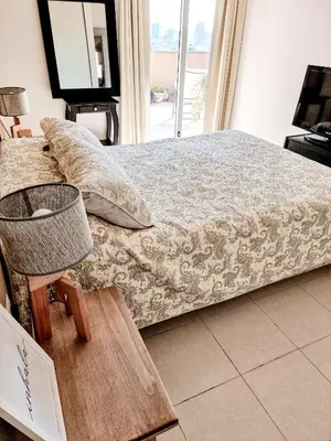 a bedroom with a bed and a chair and a window at Dpto ob trejo - pileta asador quincho vista a las sierras in Cordoba