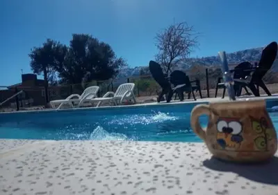 a coffee cup sitting on a table next to a swimming pool at cabañas sunrise in Merlo