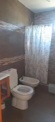 a bathroom with a toilet and a shower curtain at cabañas sunrise in Merlo