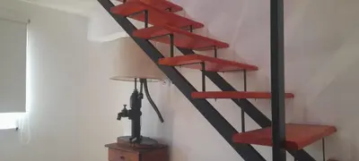 a red and black spiral staircase next to a lamp at cabañas sunrise in Merlo