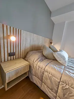 a small bedroom with a bed and a night stand at Dpto Poeta lugones 72 - pileta terraza parrilla in Cordoba