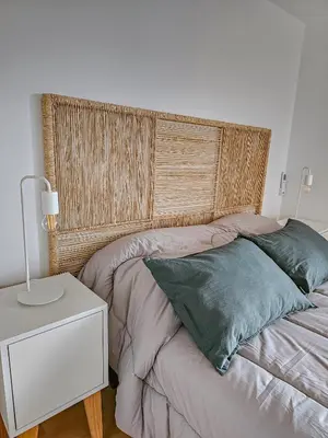 a bed with a wooden headboard next to a table at Dpto Poeta lugones 72 - pileta terraza parrilla in Cordoba