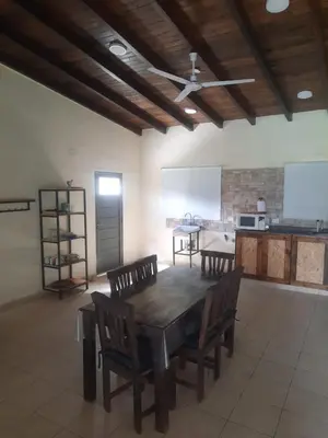 a dining room with a table and chairs and a kitchen at Cabaña La Kalma in Santa María