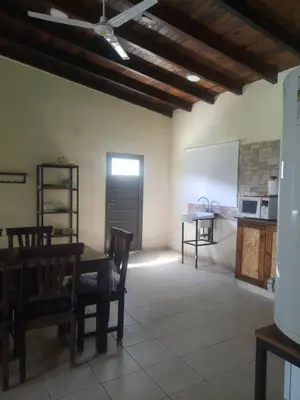 a room with a table and chairs and a kitchen at Cabaña La Kalma in Santa María