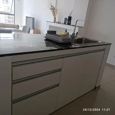 a kitchen counter with a sink and a living room at plazaColon in Cordoba