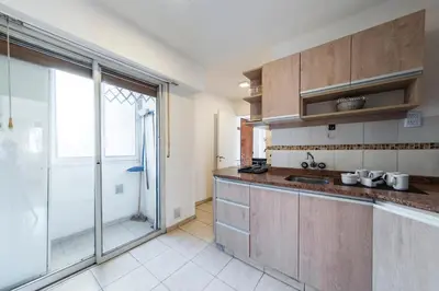 a kitchen with wooden cabinets and a large window at Cómodo Departamento en Pleno Centro in Cordoba
