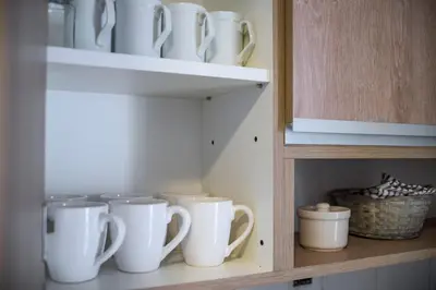 a bunch of white cups sitting on a shelf at Cómodo Departamento en Pleno Centro in Cordoba