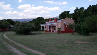a red house in a field with a dirt road at Las icarias in Las Calles