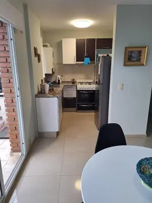 a kitchen with white appliances and a table in a room at Departamento en Torre Serena in Villa Carlos Paz
