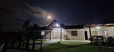 a house with a flag on the side of it at night at Cabañas cerro pelado in San Roque