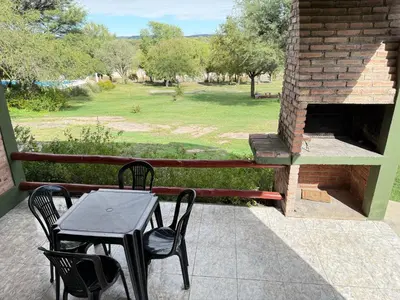 a table and chairs on a patio with a brick oven at Vista al río 2 dormitorios in Arroyo de Los Patos
