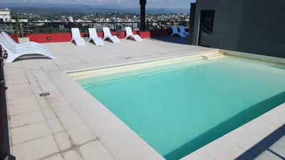 a swimming pool with white chairs on a building at Miralejos 16 Apartamento in Villa Carlos Paz