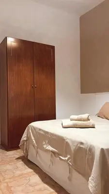 a bedroom with a bed and a wooden cabinet at Casa Criselo Multiespacio in Cordoba