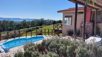 a villa with a swimming pool in front of a house at Cabaña Tanti Montaña del Vigía in Tanti