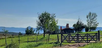 a wooden fence in a field with a house at Cabaña Tanti Montaña del Vigía in Tanti